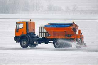 Caminhão jogando mistura de sal, cloreto de cálcio e areia para dificultar a formação de gelo nas estradas